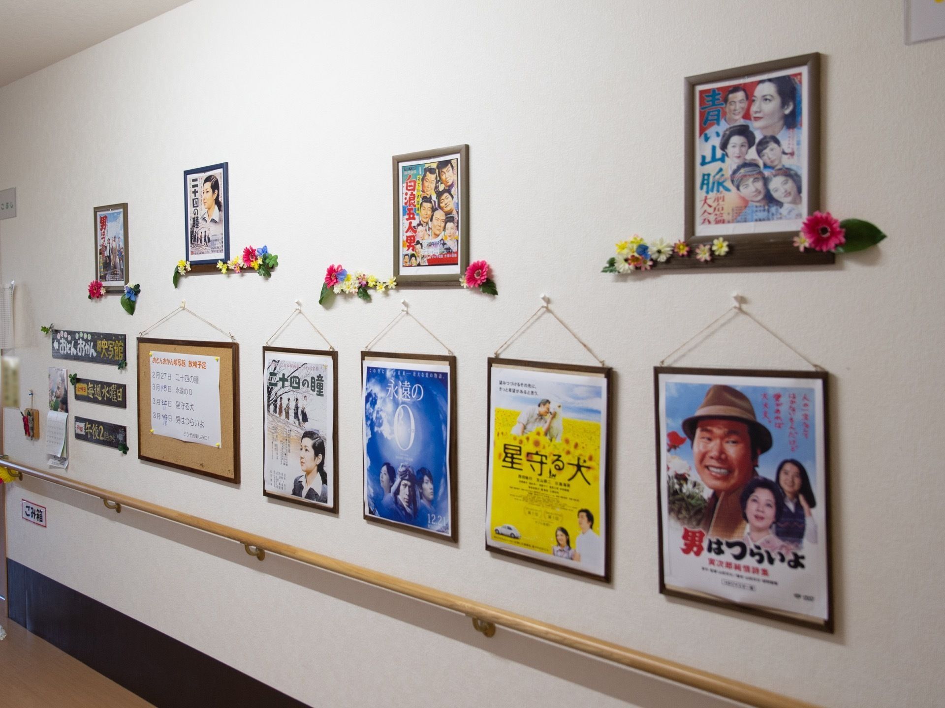 廊下の白い壁には懐かしい昔の映画のポスターが飾られている。お花なども一緒に飾られており華やかな雰囲気である。