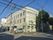 施設の建物は3階建てで、右側の壁面には大きく施設名が表示されている。玄関前には駐車場があり、右側には自転車が止められている。
