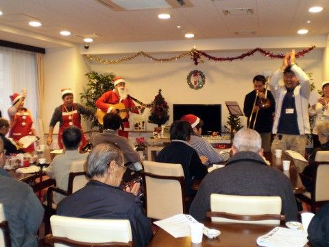 季節のイベントに合わせて仮装して楽器を演奏する人々と、それを楽しむ高齢者様