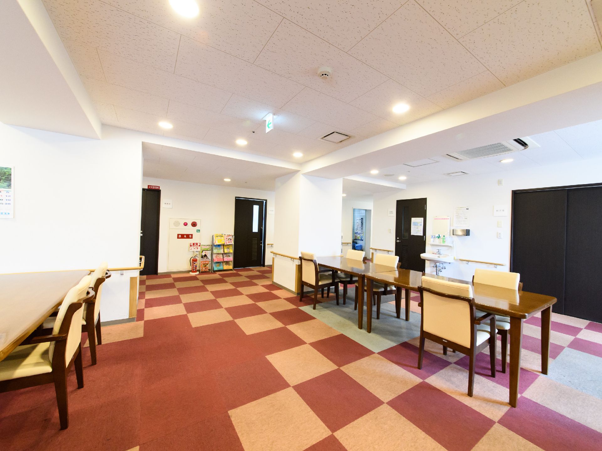 食堂には三つのテーブルがあり、椅子が六脚並べてある。床は赤と白のカーペットが敷いてある。壁には手すりがあり、洗面所が一つある。