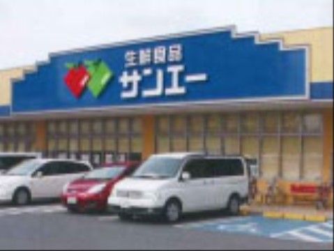 生鮮食品を売るスーパーがある。建物は1階建てで正面の青色が目立ち、店舗前の駐車場に車が数台駐車されている。