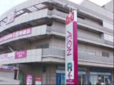 駐車場を兼ねた、大きな建物がある。建物前には、店舗名や駐車場を示すマーク入りの案内板が設置されている。