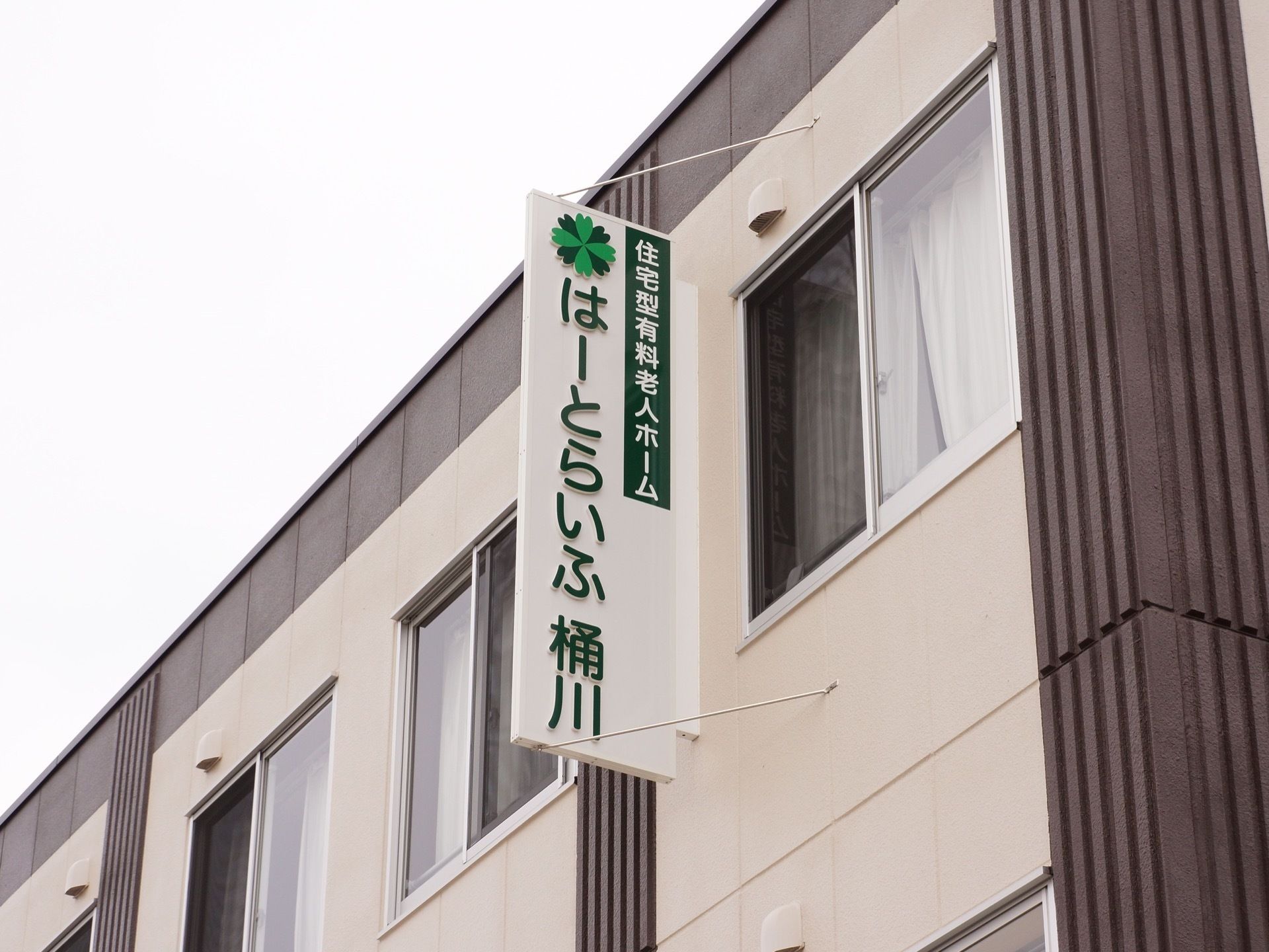 施設の外壁に取り付けられた、緑色を基調にした施設の看板