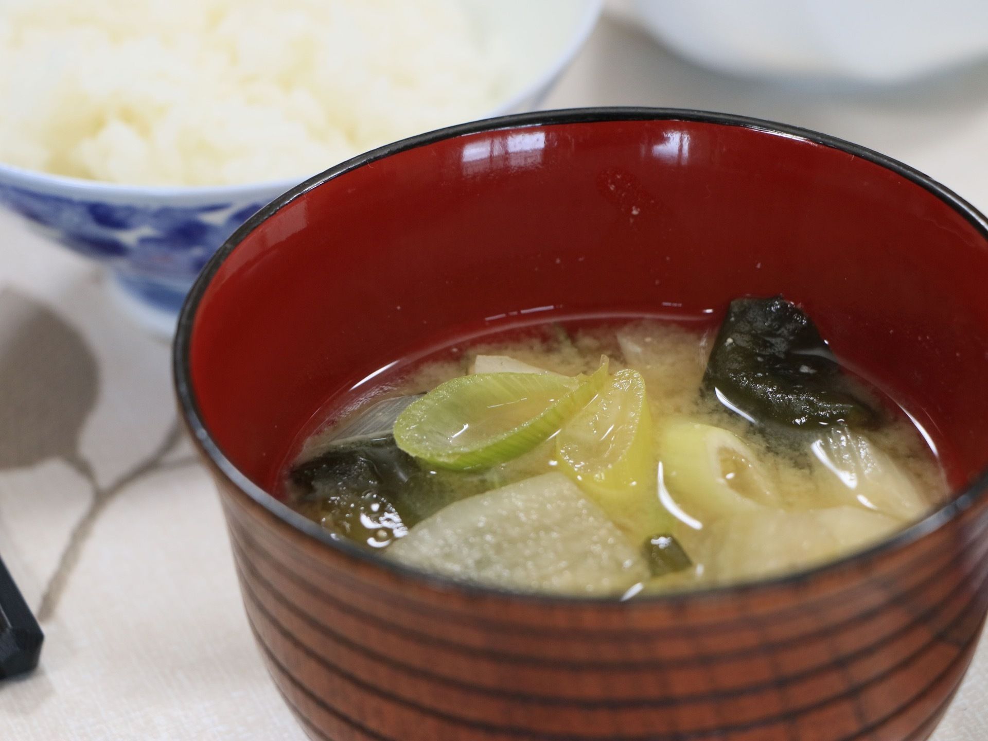 お椀にはお味噌汁が入れられている。ネギや大根、ワカメといった材料が使われており、具だくさんになっている。