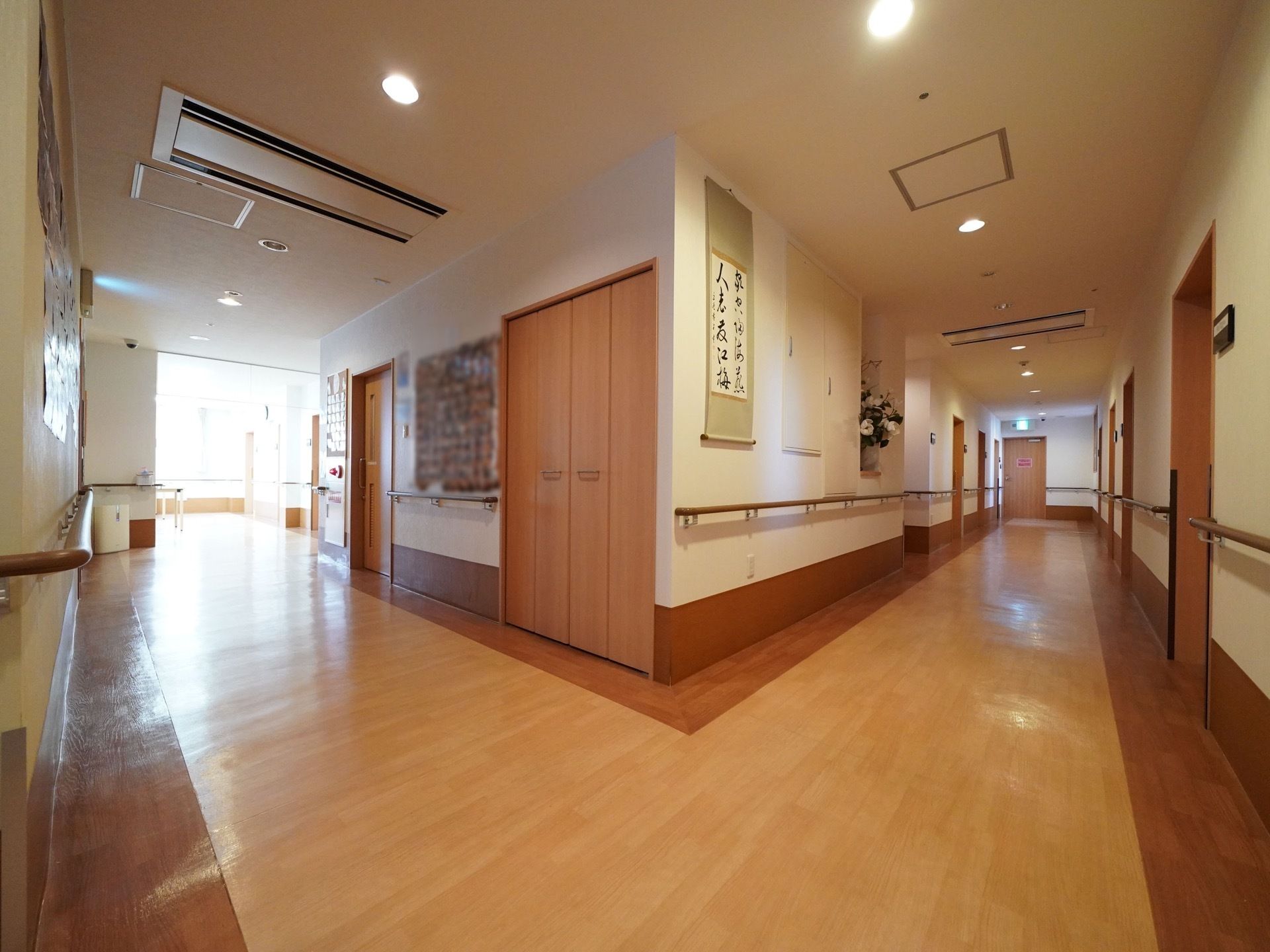 入居者様が安全に利用できるように、廊下の道幅は広く造られている。花や掛け軸が飾られ、居心地の良いアットホームな雰囲気になっている。