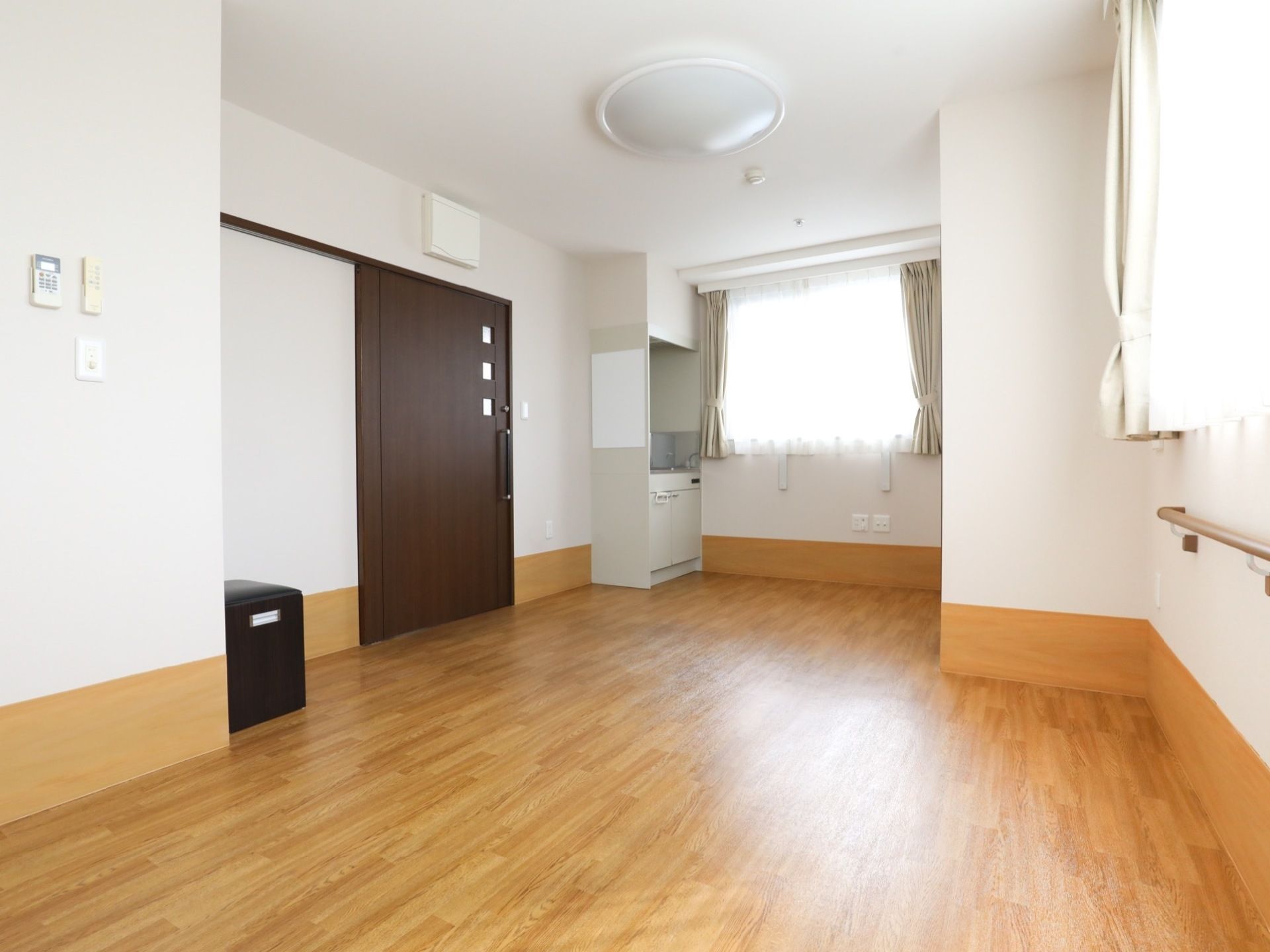 壁と天井が白色で、床はフローリングのゆったりとした広さの居室である。キッチンもあり、くつろいで過ごすことができる。