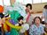 風船で作った大きな花束とミッキーマウスの横に、椅子に座った女性の入居者様がいる。その後ろで、にこやかな表情をしたスタッフが付き添っている。