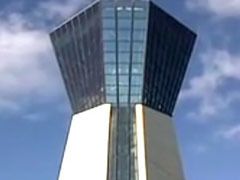 青い空をバックにそびえるように建っているタワーは、下部が白い壁面で上部は全面ガラス張りの展望台になっている。