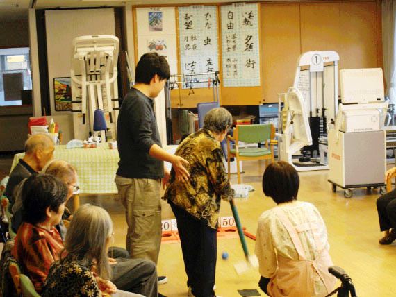 施設内の運動器具が置かれた部屋で、スタッフとゲームを楽しむ高齢者様