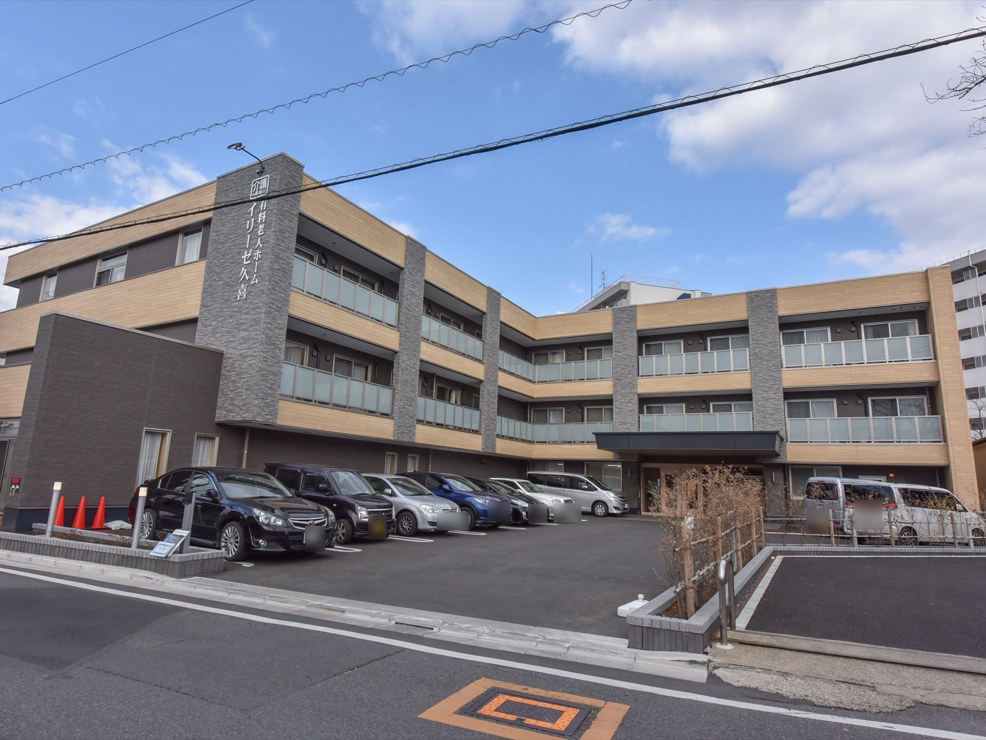 道路沿いに建てられた施設の外観はグレーを基調とした落ち着いた雰囲気になっている。敷地内に駐車スペースが設けられている。