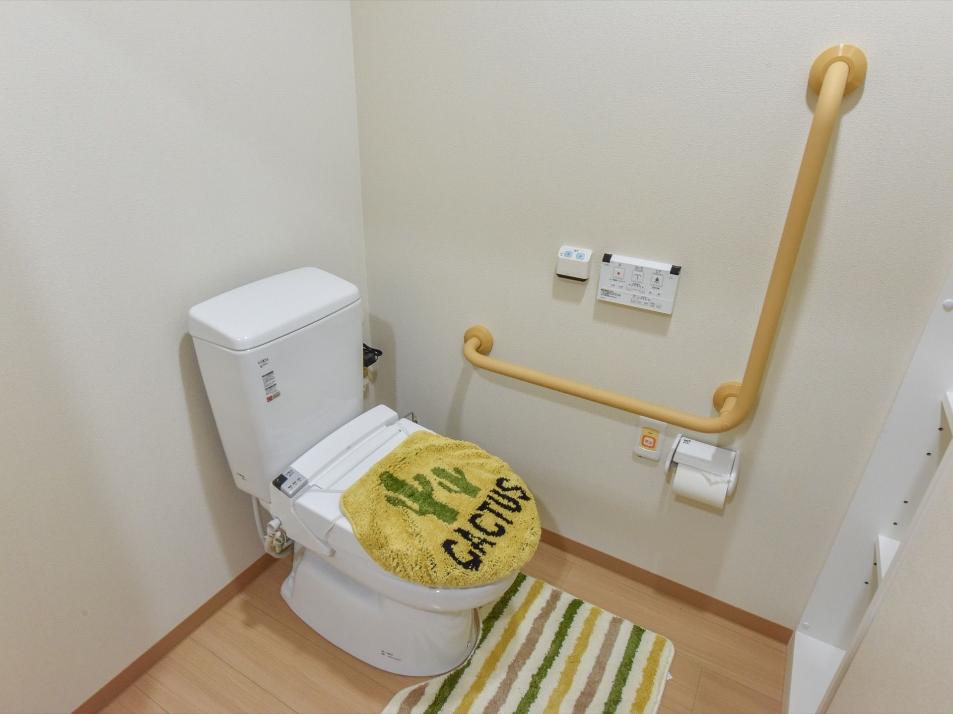 清潔感があるトイレには前面に収納スペースが設けられている。壁には手すり、緊急通報装置が設置されている。