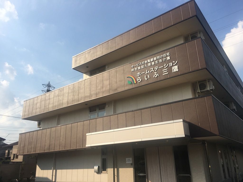 木陰を散歩する車椅子に乗った高齢女性と介助をする女性ヘルパー