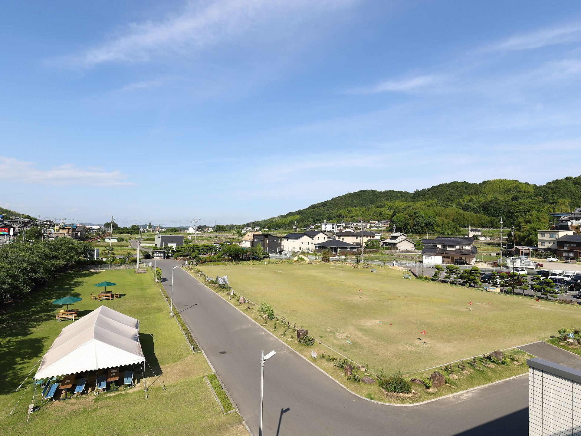 芝の敷かれているグラウンドには、L字の道路がある。テントも設置されており、中にはテーブルやいすも置かれている。
