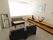 日当たりの良い部屋にグレー調のソファーが置いてある。棚の上に置物がかざってあり、壁には絵画を飾ってある。