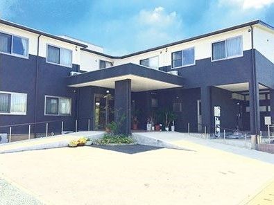 緩やかなスロープと手すりが設置された、二階建ての施設の玄関口