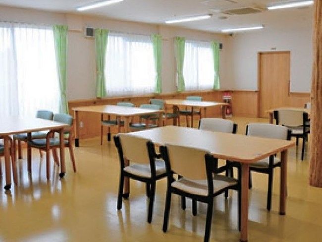広い空間のリビングには、中央に椅子やテーブルがたくさん並べられている。奥には、引戸が1つ取りつけられている。
