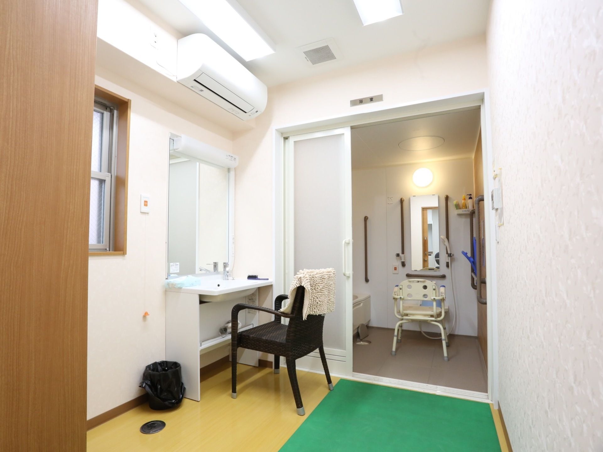 浴室には、背もたれやひじ掛けがある椅子が置かれている。脱衣所には、洗面台とエアコンが設置されている。