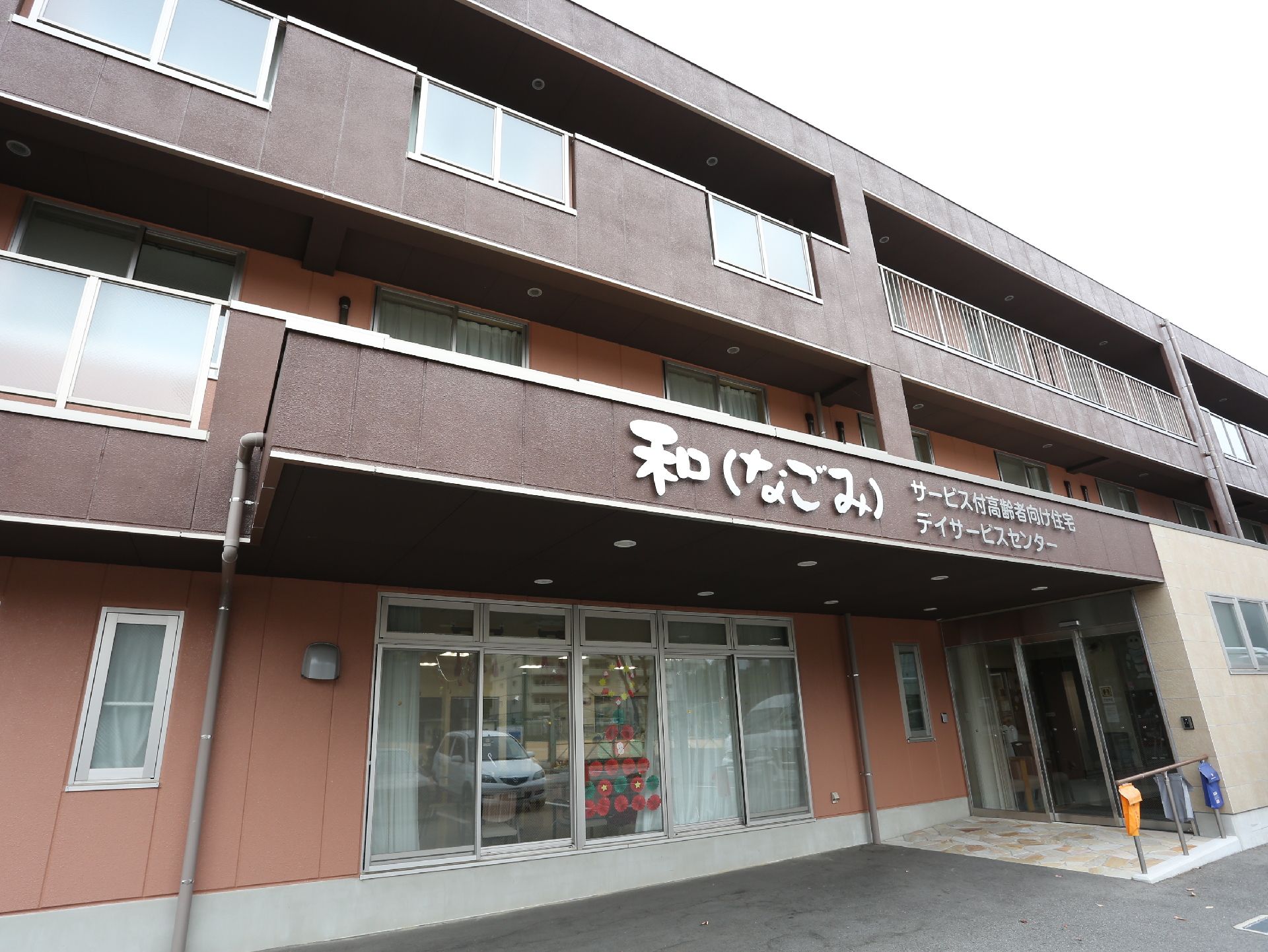 落ち着いたブラウンの外壁の、バリアフリーに配慮して作られた三階建ての施設