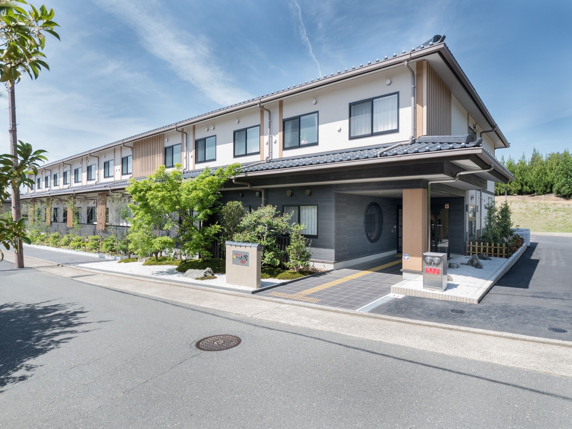 2階建ての和風な外観の建物である。アプローチには大きな屋根がある。周囲に石は植物が置かれた日本庭園がある。