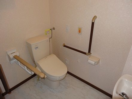 トイレ内は広いスペースが確保されており、手洗い器も置かれている。便座周りには、手すりがしっかりと設置されている。