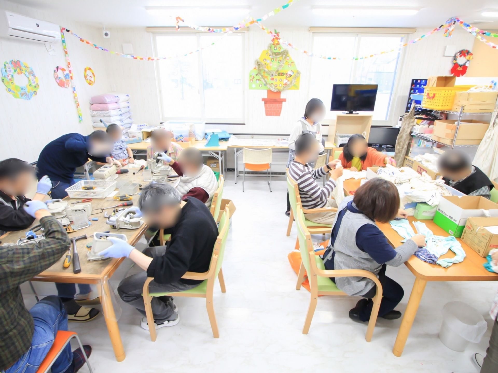 大きな窓によって太陽光が差し込み、明るく開放的なホールとなっている。机や椅子、テレビが設置されている。