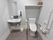 洋式トイレに加え、手洗い場も併設されているタイプのトイレ。洋式トイレの上には、棚がある。手洗い場には鏡も付いている。