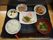 白ご飯、味噌汁、メイン料理、副菜、漬け物がトレーに置かれている。入居者様の健康的な生活を支えている。