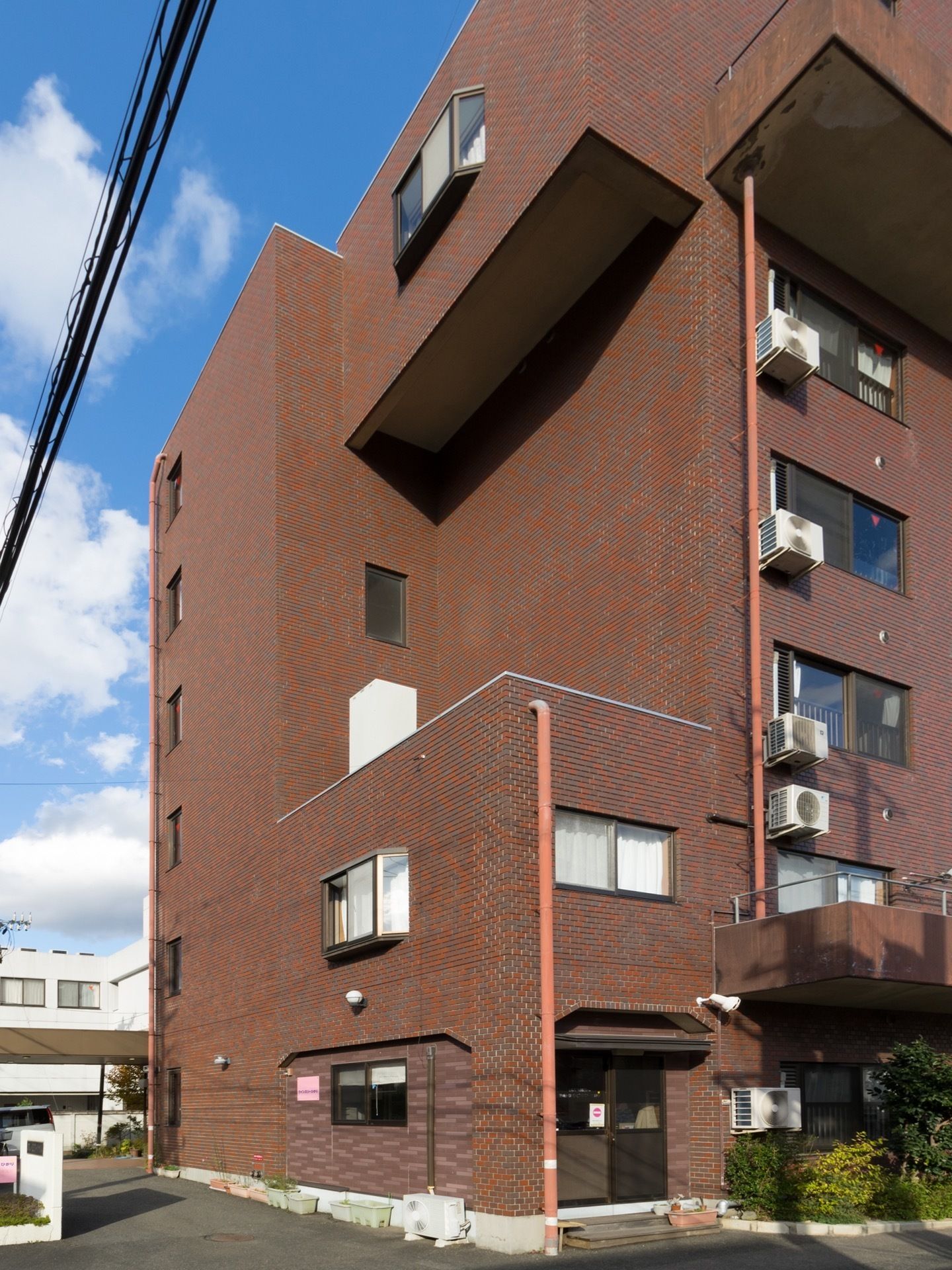 ブラウンのレンガ調の外壁が落ち着いた雰囲気の施設の周囲はコンクリートできれいに整備され、木が植えられている。
