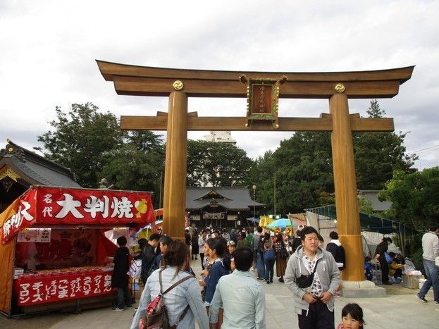 近くにある神社の大鳥居とたくさんの人々。毎年お祭りが盛大に行われ、食べ物などの屋台が出て多くの人で賑わう。