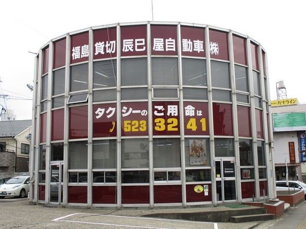 外観が円形をした、ユニークなデザインの地元タクシー会社。ブラウンの外壁に会社名と電話番号が書かれている。