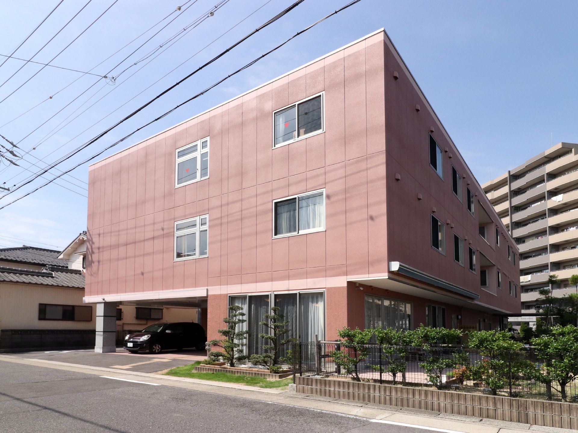 施設前と道路はフラットになっているので、車椅子の人や足が悪い方などが歩きやすいようになっている。敷地のフェンスそばは、低木が植えてある。