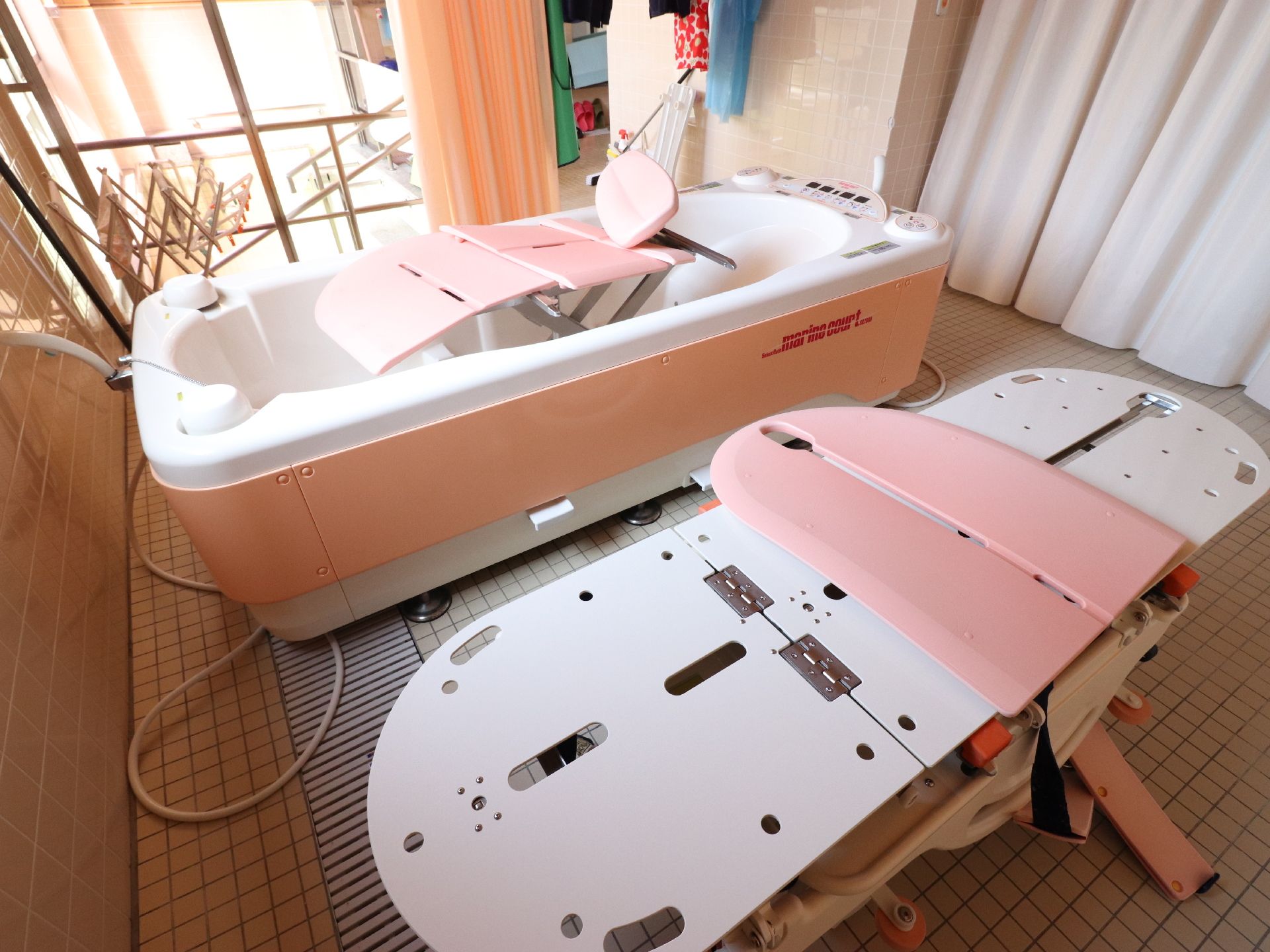 室内物干し器が置いてある。介助用のバスタブにはシャワーも完備している。壁に緊急時呼び出しすることができるブザーが取り付けてある。