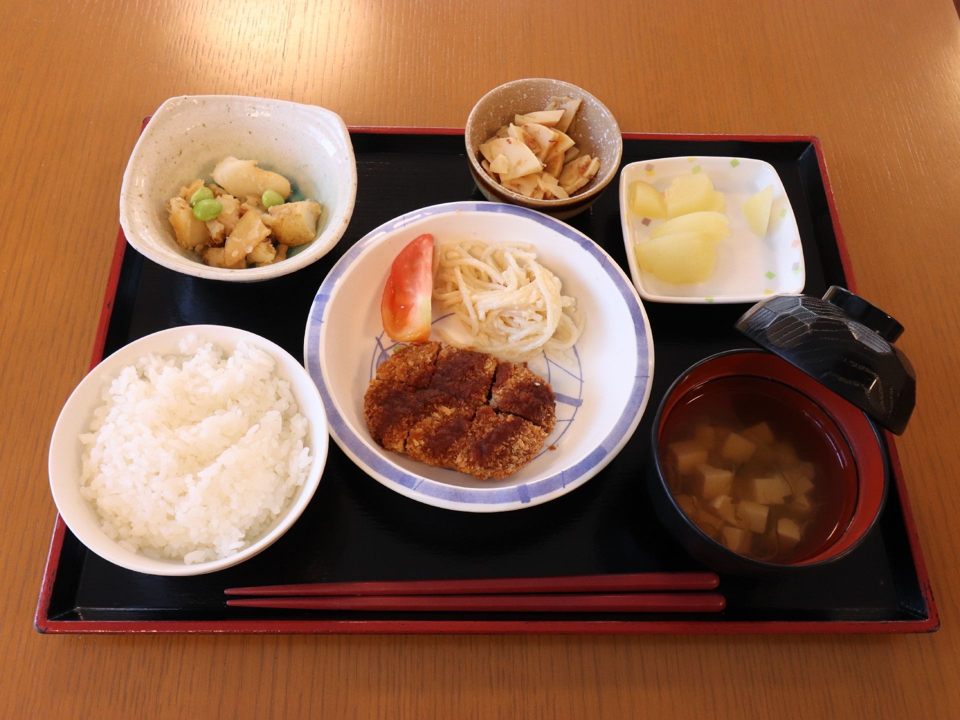 赤い箸が一膳ついている。ごはん、お椀のほかに、惣菜がついている。