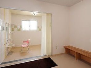 脱衣所と浴室の間はカーテンで仕切られており、段差がない。シャワーの前にはバスチェアがある。高い位置に窓がある。