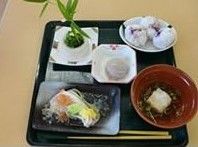 黒の四角いトレーに、料理とお箸が並べられている。お椀に入った汁物や、四角や丸い器に入ったおかず類が用意されている。