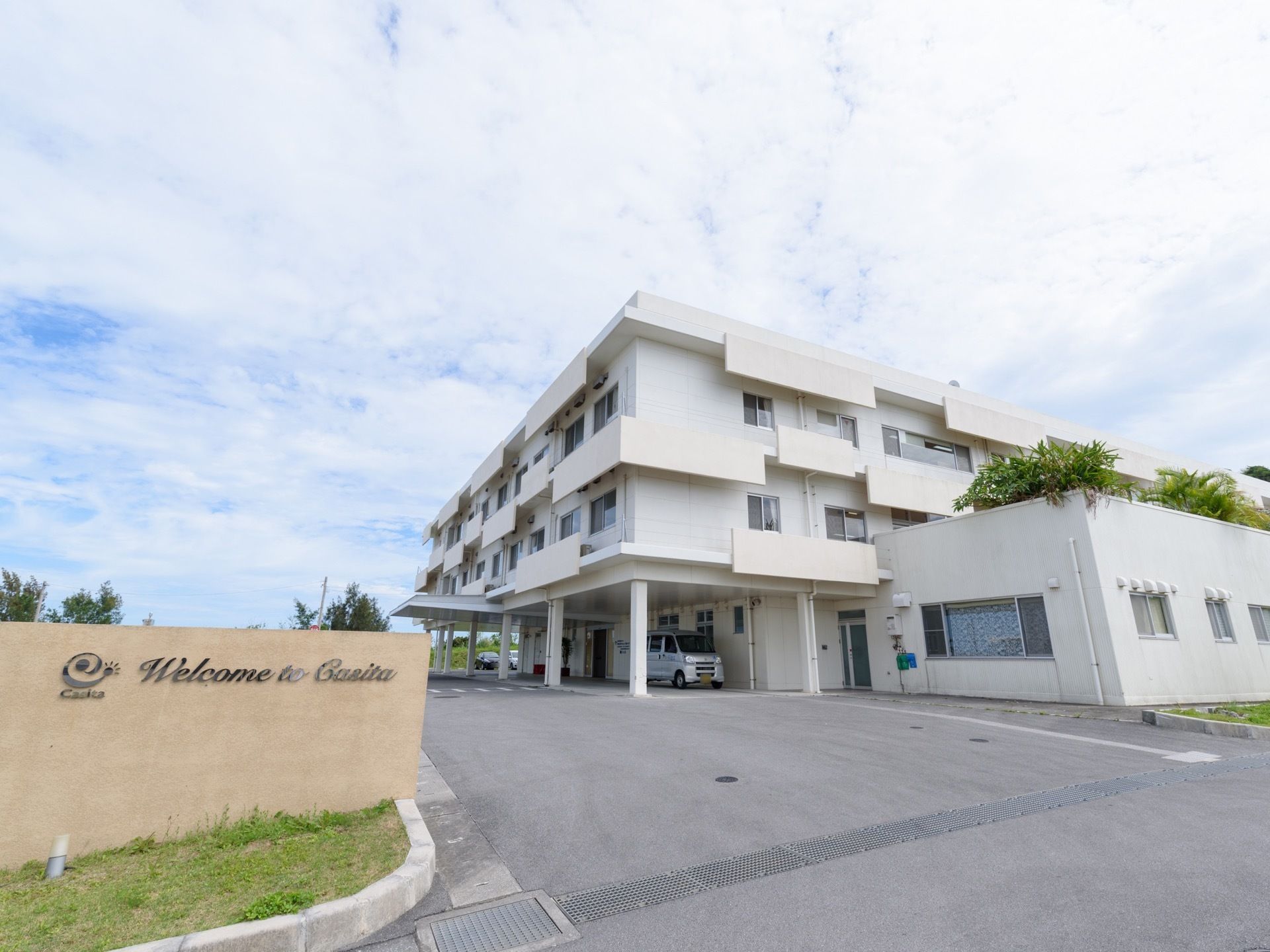 白い３階建ての建物で、エントランスは屋根付きで車寄せがあるので天候の悪い日も安心して出入りすることができる。
