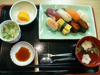 黒いトレーの上に、寿司、お漬物、お吸い物、茶わん蒸しがきれいに並んでいる。お箸やスプーン、フォークも用意されている。