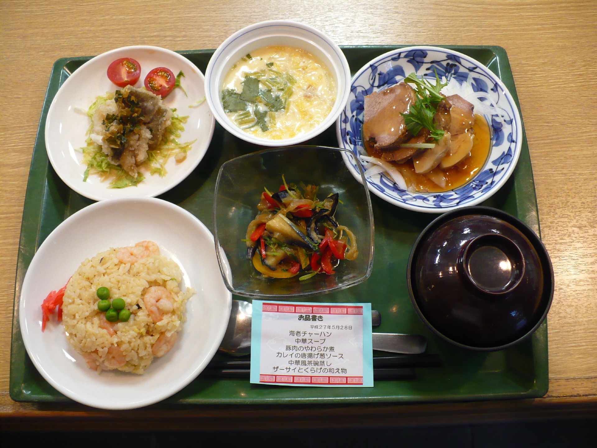 緑色のトレーの上に、チャーハン、スープ、お肉などの食材がのっている。お品書きも付いており、カロリーや塩分量の把握も可能。