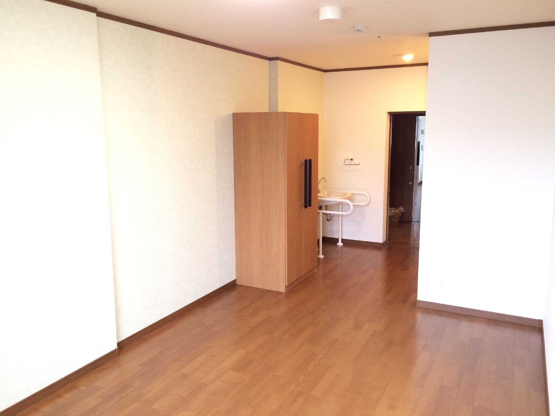 居室には焦げ茶色で両開きの扉が付いた収納庫が設置されており、入居者様の大切な洋服などを収納することができる。