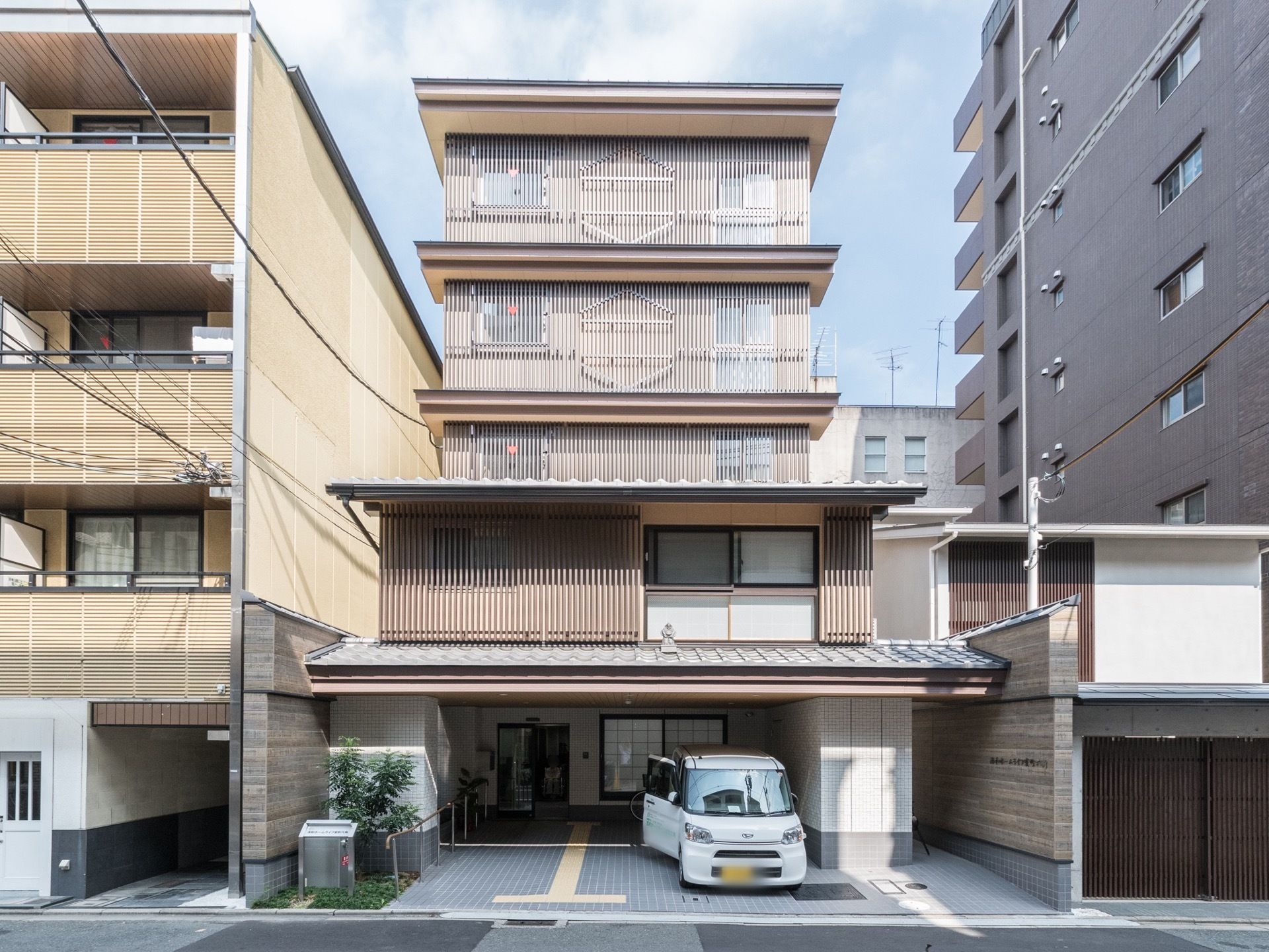 格子仕様の日本造りの外観である。１階には、玄関と駐車スペースを設けている。地面には点字ブロックを施している。