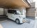 グレイ色のタイル調の地面と天井が茶色のスペースに施設専用の車を停めている。横側の茶色のデザイン仕様の外壁に施設名を施している。