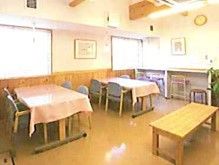 食堂にはテーブル２台と椅子が複数置かれている。奥にはカウンター席も設けられている。窓から光が入り、明るい室内である。