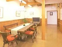 広々とした共有スペースには、縦に長いテーブルとたくさんの椅子が設けられている。テーブルの奥にはテレビが置かれている。