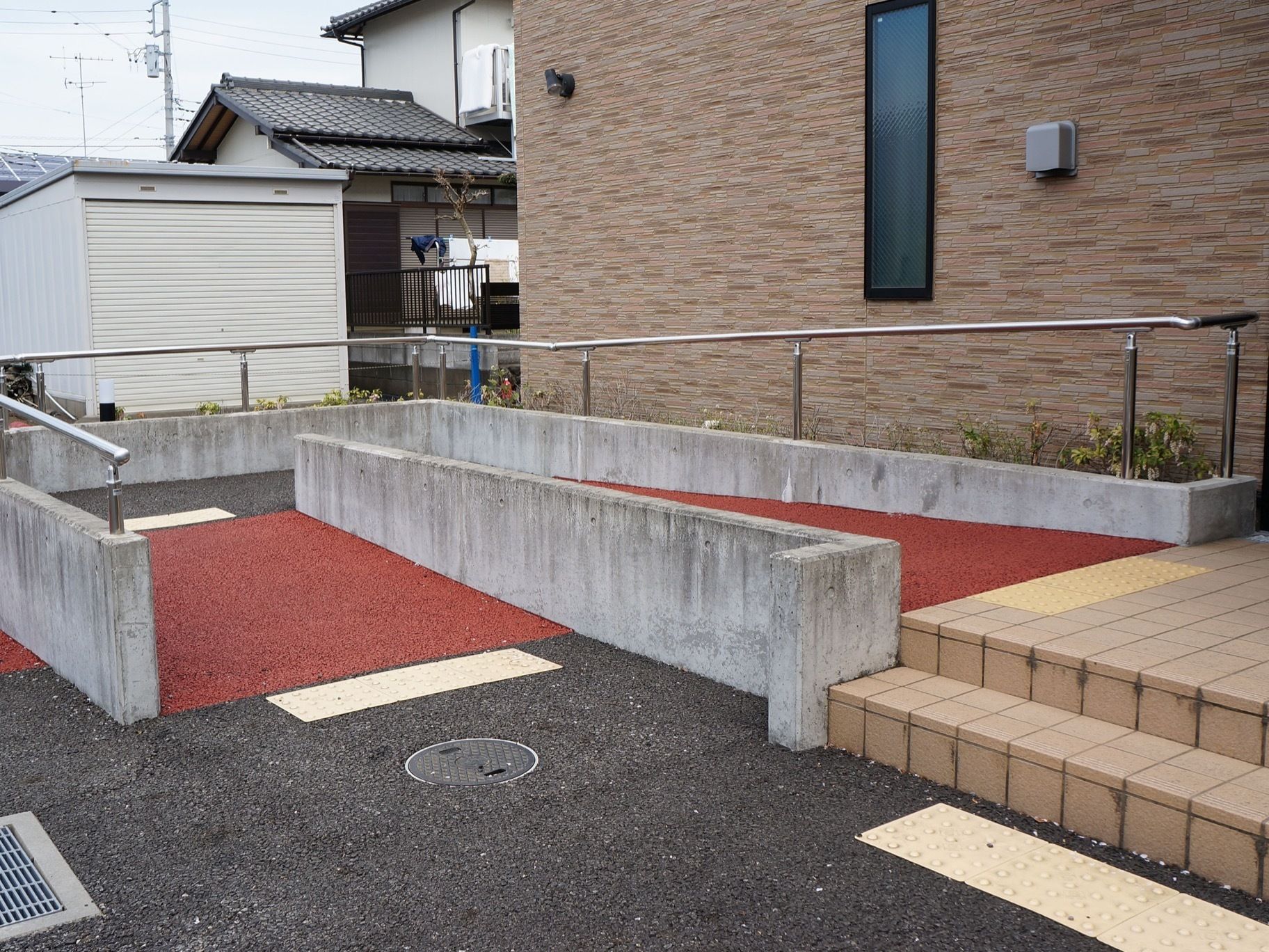 建物の外に、アスファルトで造られたスロープが備わっている。コンクリートの壁には手すりも設置されている。