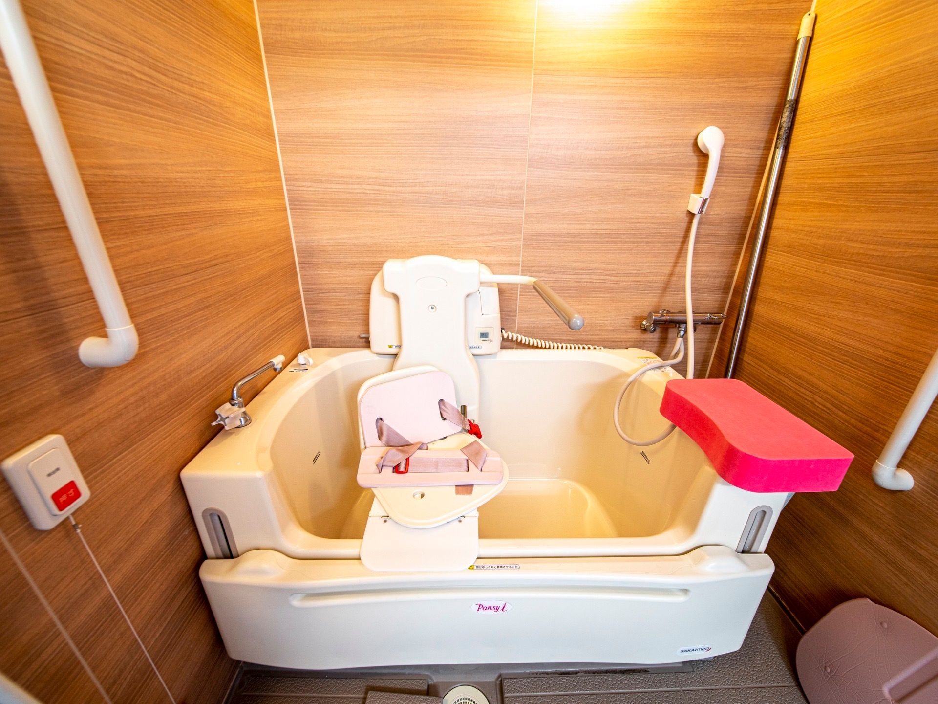 浴槽の手前が上下する仕組みになっていて、椅子型のストレッチャーが取りつけられている入浴装置が浴室に据えてある。