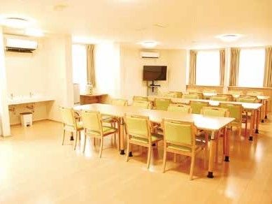 壁にかけたTVの近くに８人掛けのテーブルを３列並べた部屋