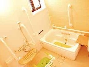 背もたれのついたシャワーチェアが置かれている。湯温は調節できるようになっている。壁は木目調になっており、温かい雰囲気である。