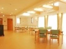 あたたかい光が差し込む開放的なリビングである。フローリングの床の上に、テーブルや椅子が複数置かれている。