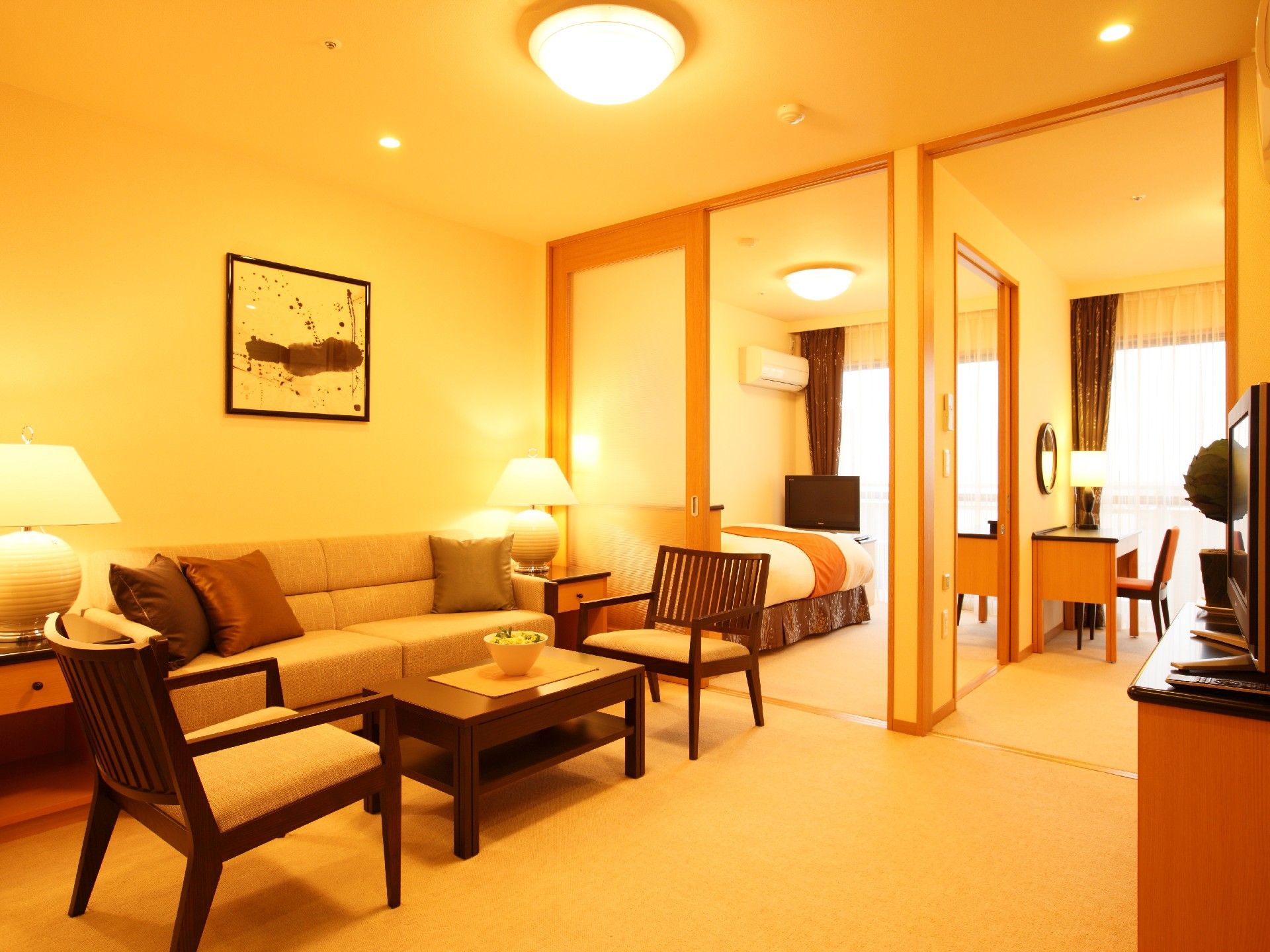 手前にはソファセットが置かれている。奥には寝室が２部屋あり、間はドアと壁で仕切っている。それぞれ突き当りに窓、壁際にベッド、エアコンがある。