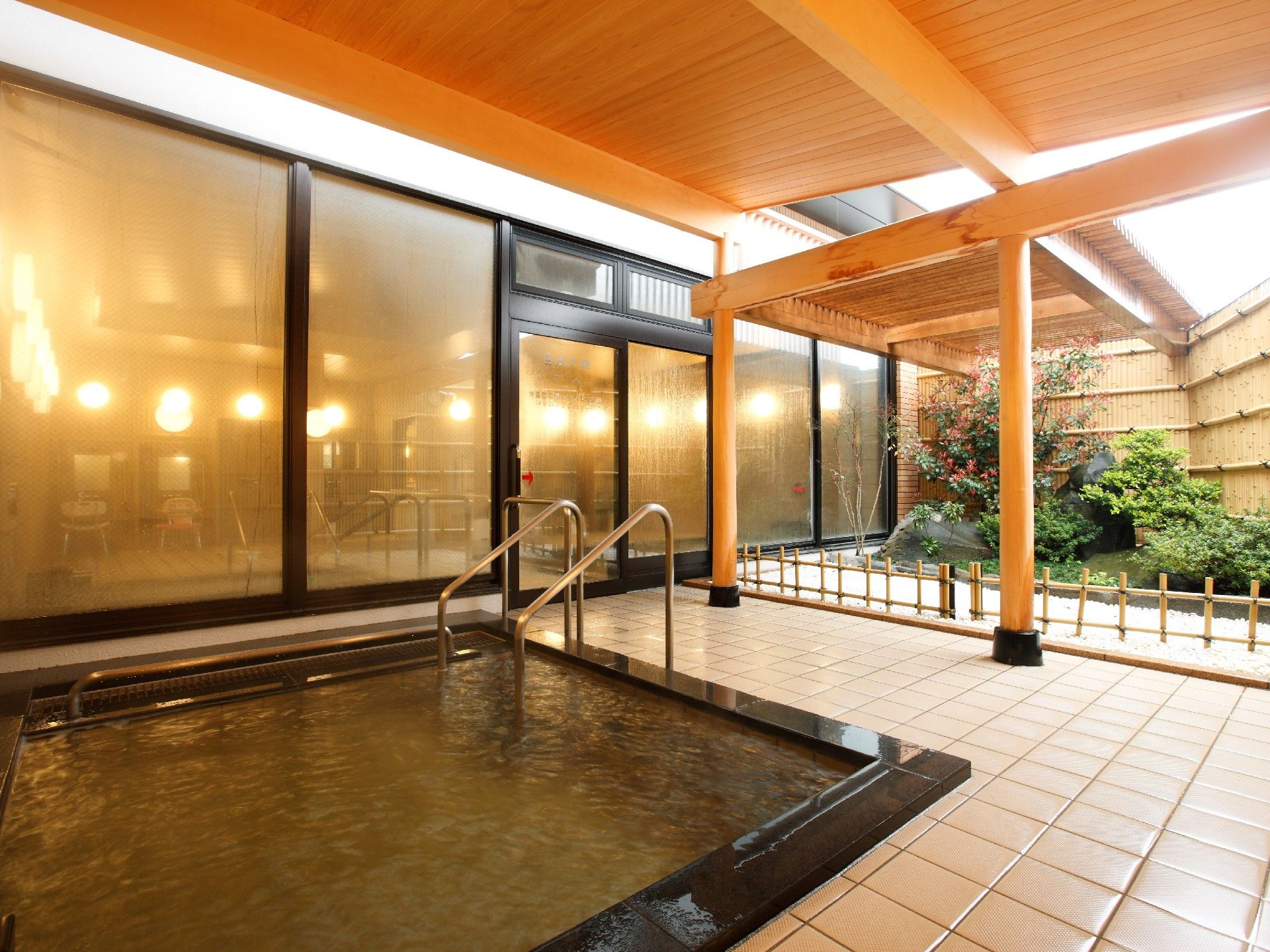 内湯から続く小さな日本庭園を備えた屋根付きの露天風呂